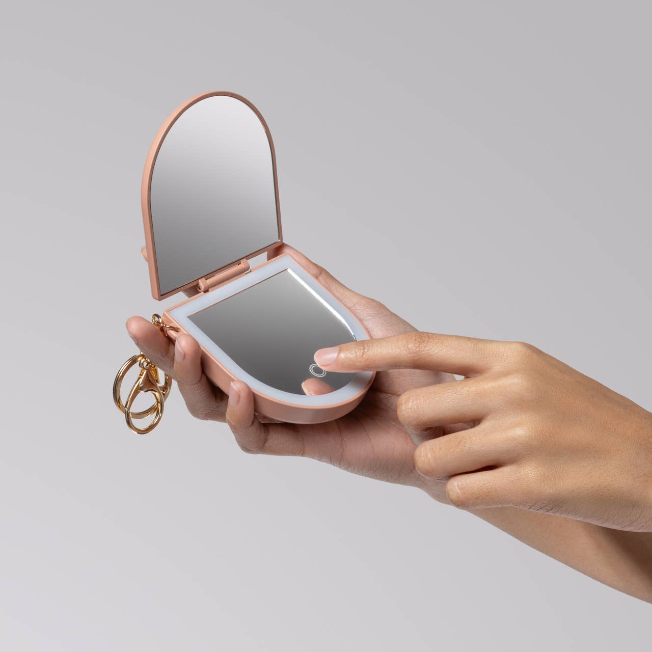 Terracotta Compact Mirror Keychain with LED, held in hands, featuring dual mirrors and touch-sensitive light, plus key-ring chain for easy attachment.