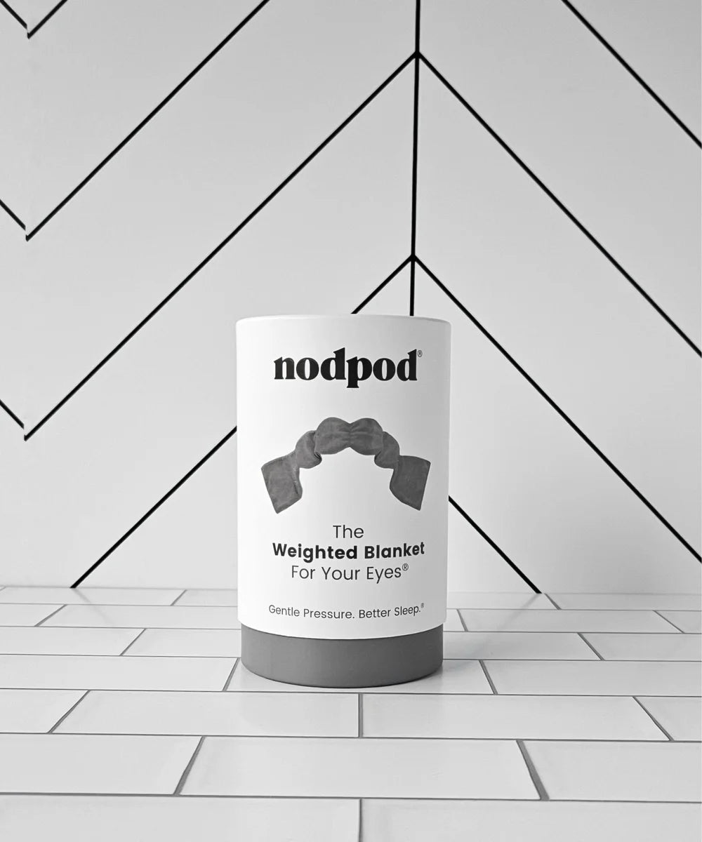 Nodpod's cylindrical canister labeled The Weighted Blanket For Your Eyes, packaging their strap-free, soothing weighted eye pillow for relaxation and better sleep.