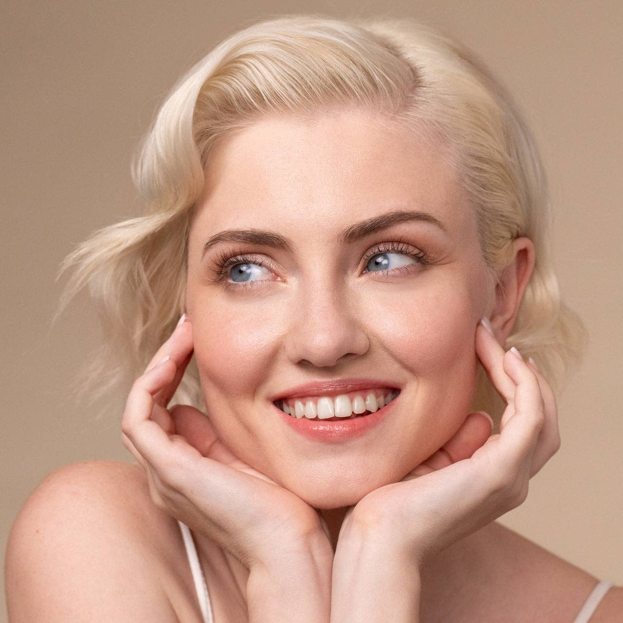 Young woman with wavy platinum-blonde hair smiles, showcasing the effects of Repairing Argan Oil Conditioner for shiny, frizz-free, healthy hair.