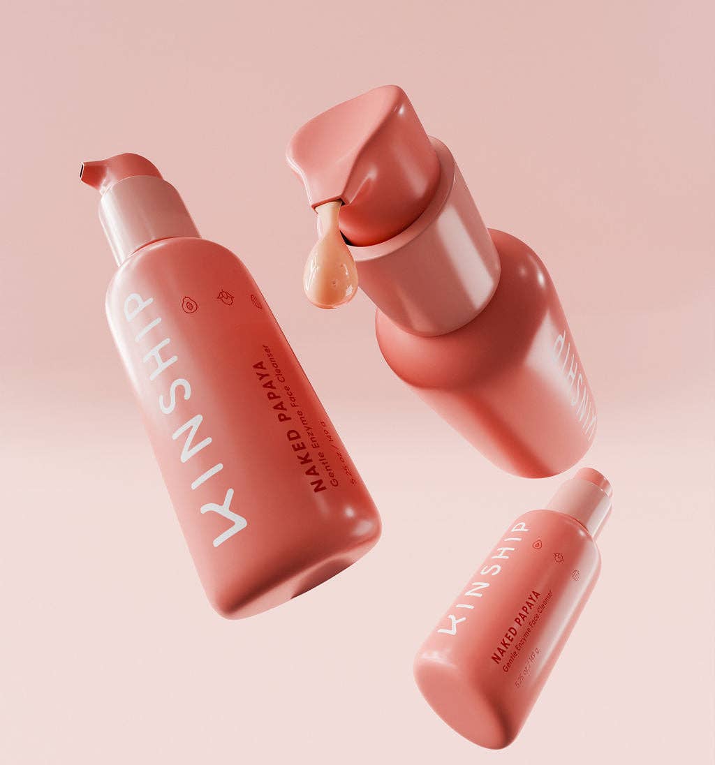 Kinship Naked Papaya Gentle Enzyme Milky Cleanser bottles, with one dispensing a drop, highlight its hydrating, makeup-removing capabilities for sensitive skin.