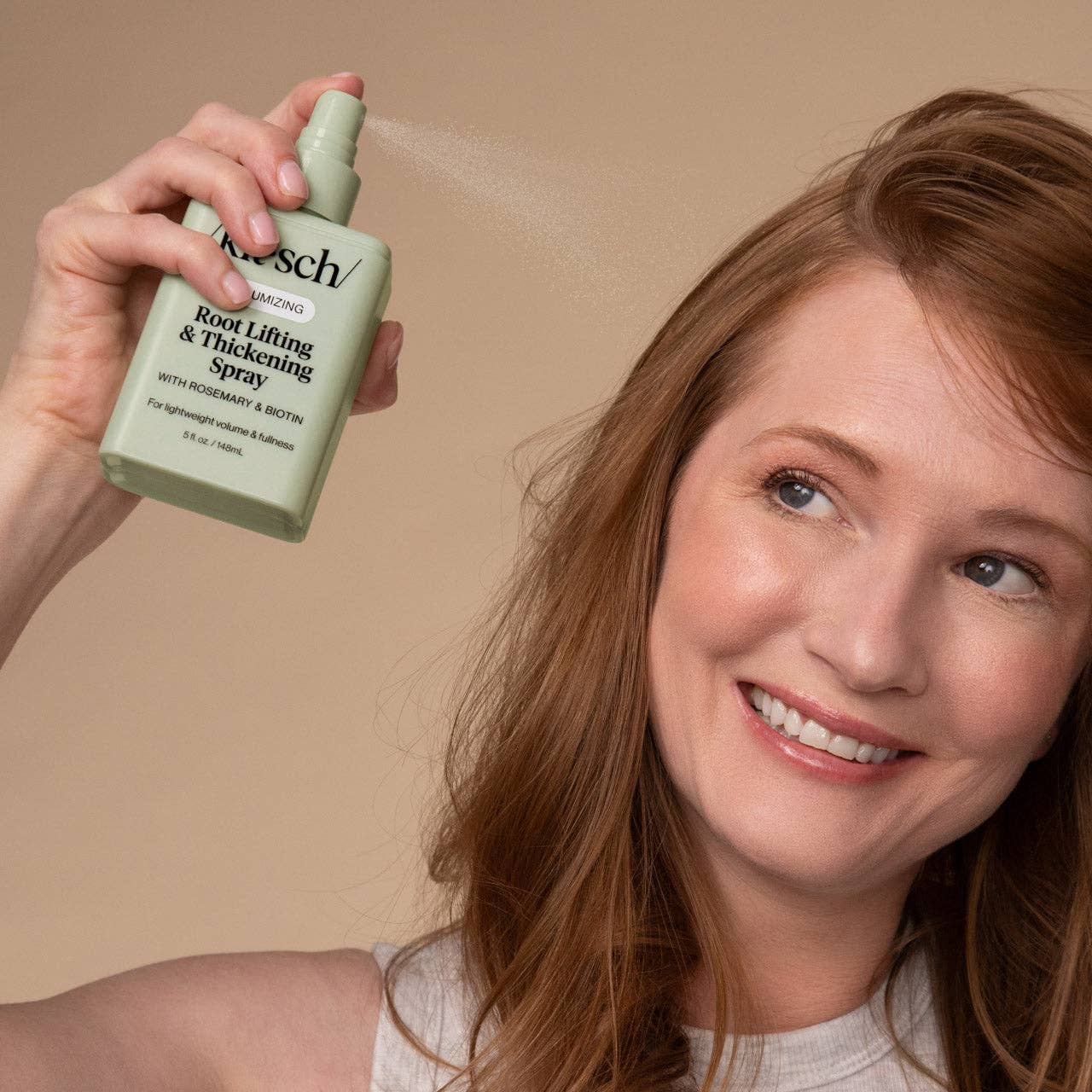 Woman applying Root Lifting & Thickening Spray at hair roots for volume, featuring rosemary and biotin, enhancing lightweight fullness.