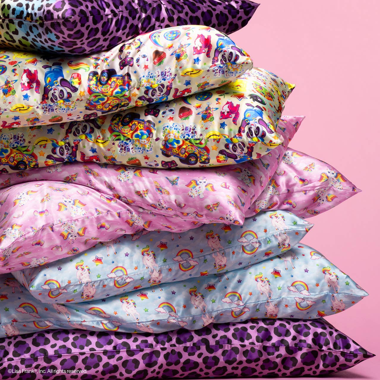 Lisa Frank x Kitsch Standard Satin Pillowcase showcasing whimsical designs like unicorns and rainbows, stacked with colorful, child-friendly pillows against a pink backdrop.