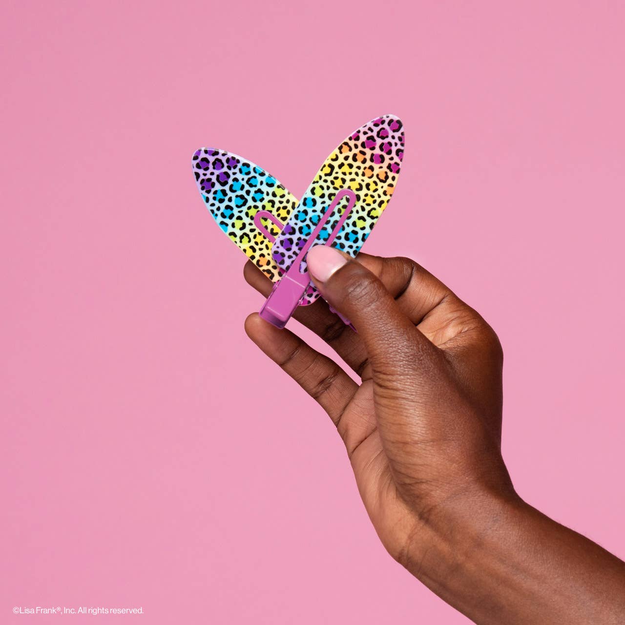 Lisa Frank x Kitsch XL Creaseless Clip in Rainbow Leopard held by hand, ideal for securing hair during makeup, prevents creases, perfect for beauty prep.