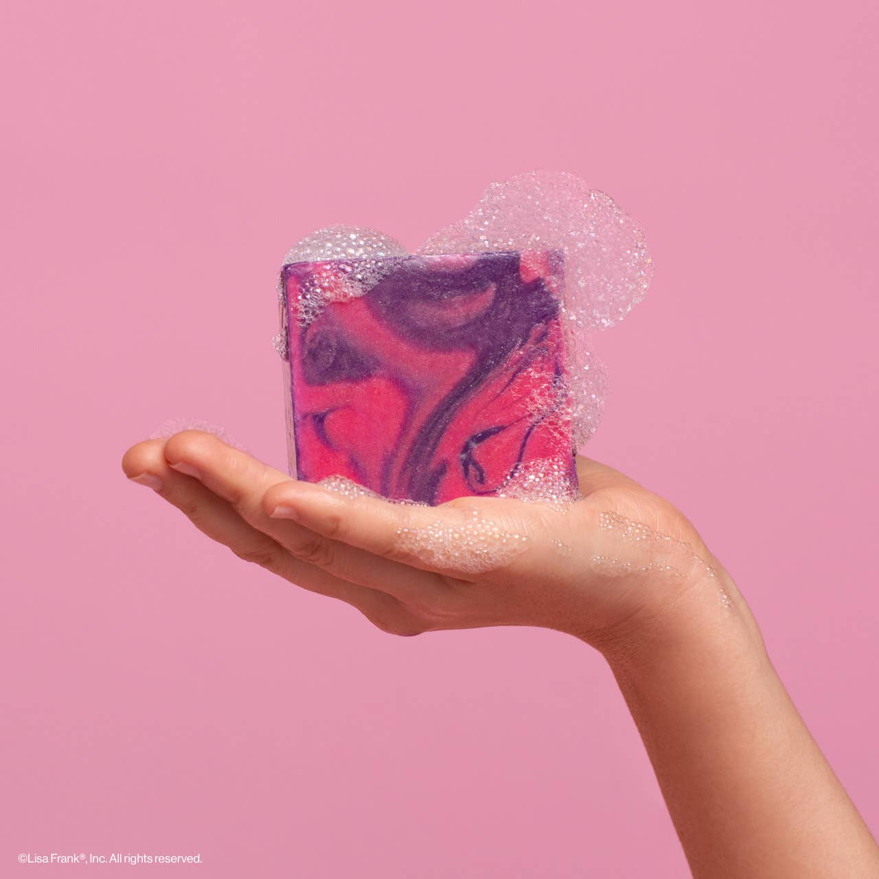 Hand holding Lisa Frank x Kitsch Dancing Dreams Body Wash Bar, marbled with pink-purple swirls, foamy lather, sustainable, vegan, cruelty-free, ideal for a gentle cleanse.