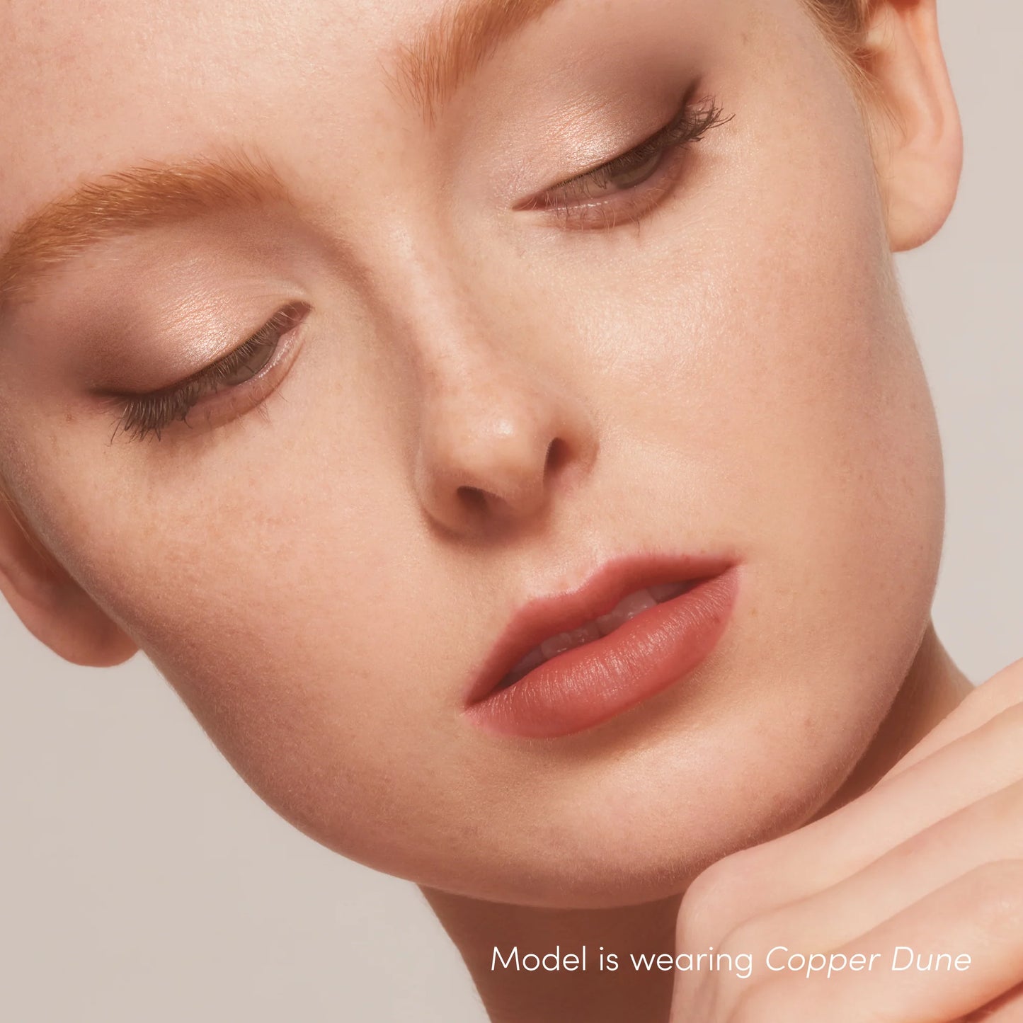 Woman with glowing skin wears ColorLuxe Hydrating Cream Lipstick in Copper Dune, showcasing vibrant, comfortable satin finish with hydrating, nourishing formula.
