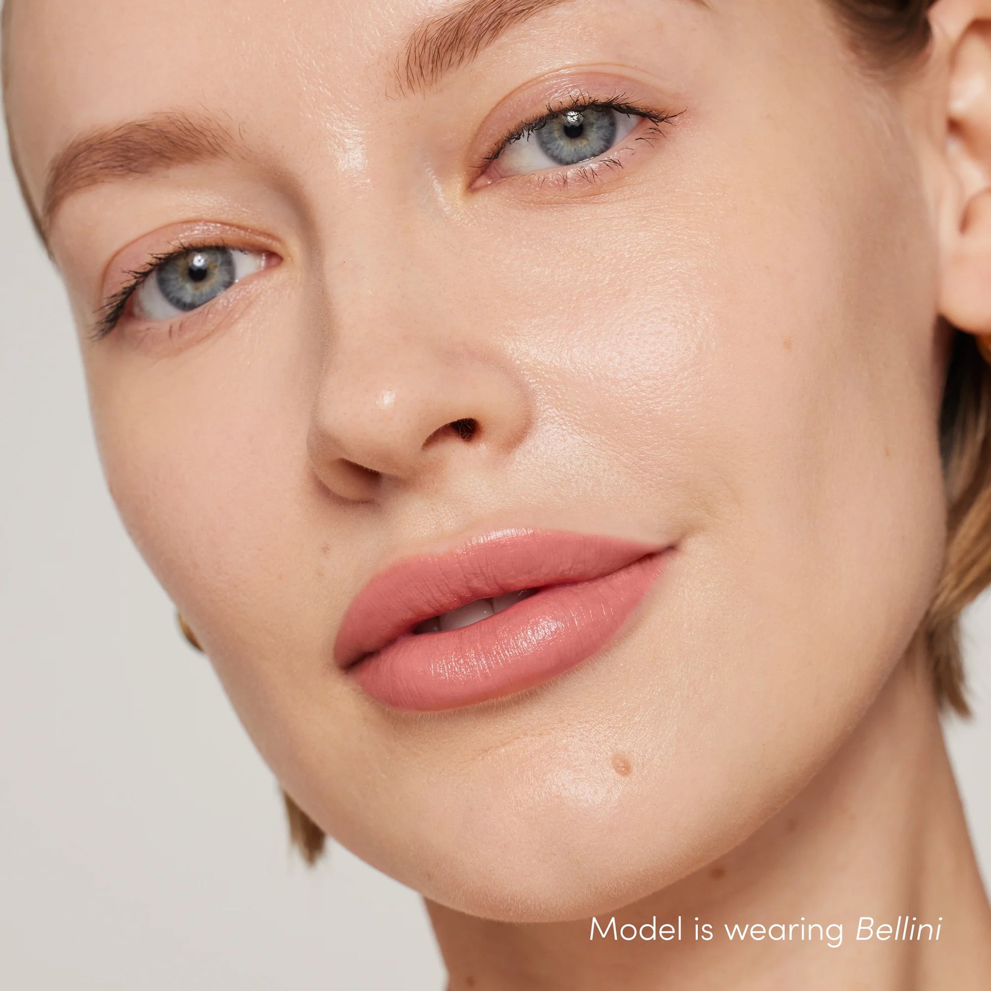 A close-up of a woman's lips wearing ColorLuxe Hydrating Cream Lipstick in Bellini, showcasing its creamy, hydrating formula and soft, muted-pink shade.