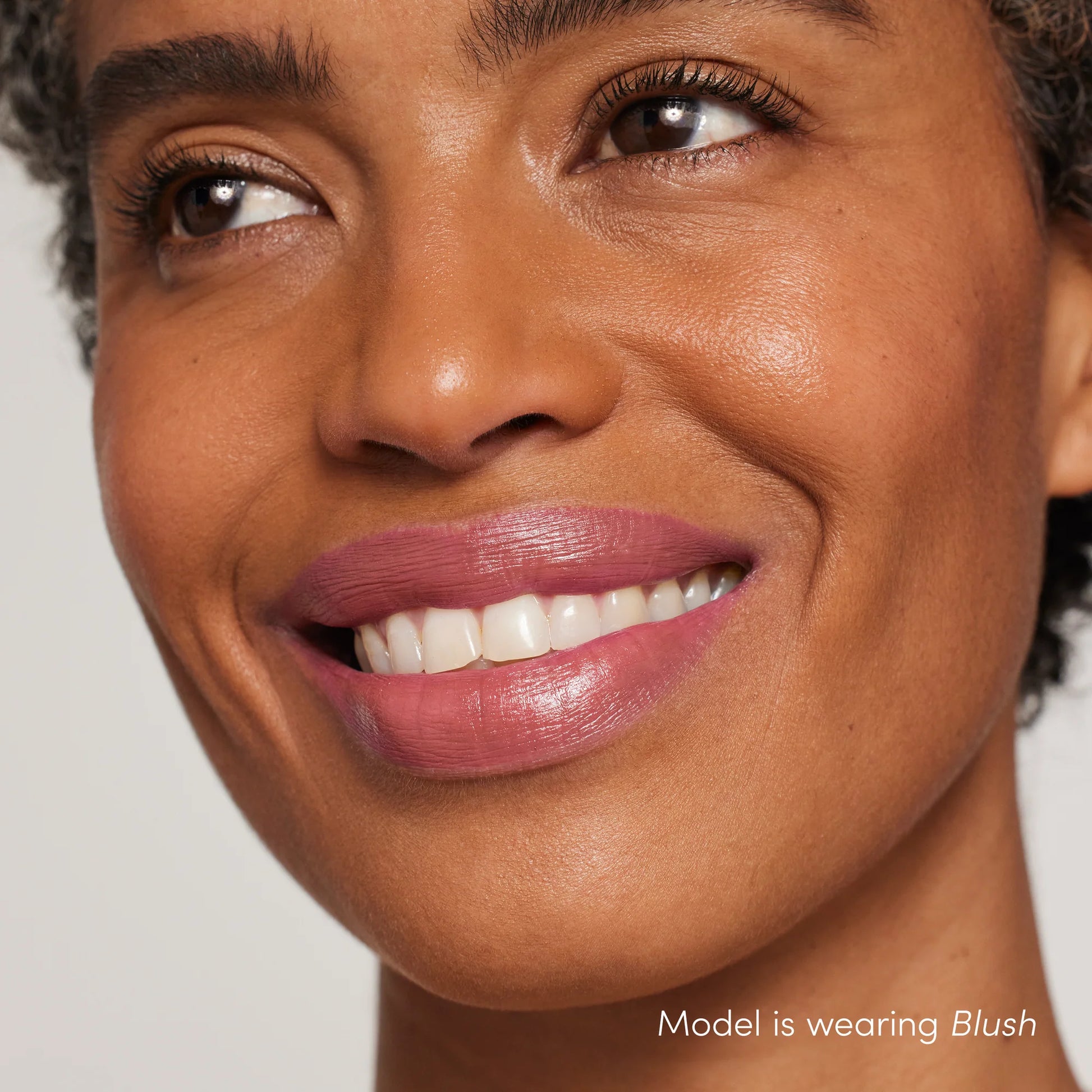 Smiling woman wearing ColorLuxe Hydrating Cream Lipstick in blush, showcasing its creamy, hydrating formula and vibrant, satin finish.