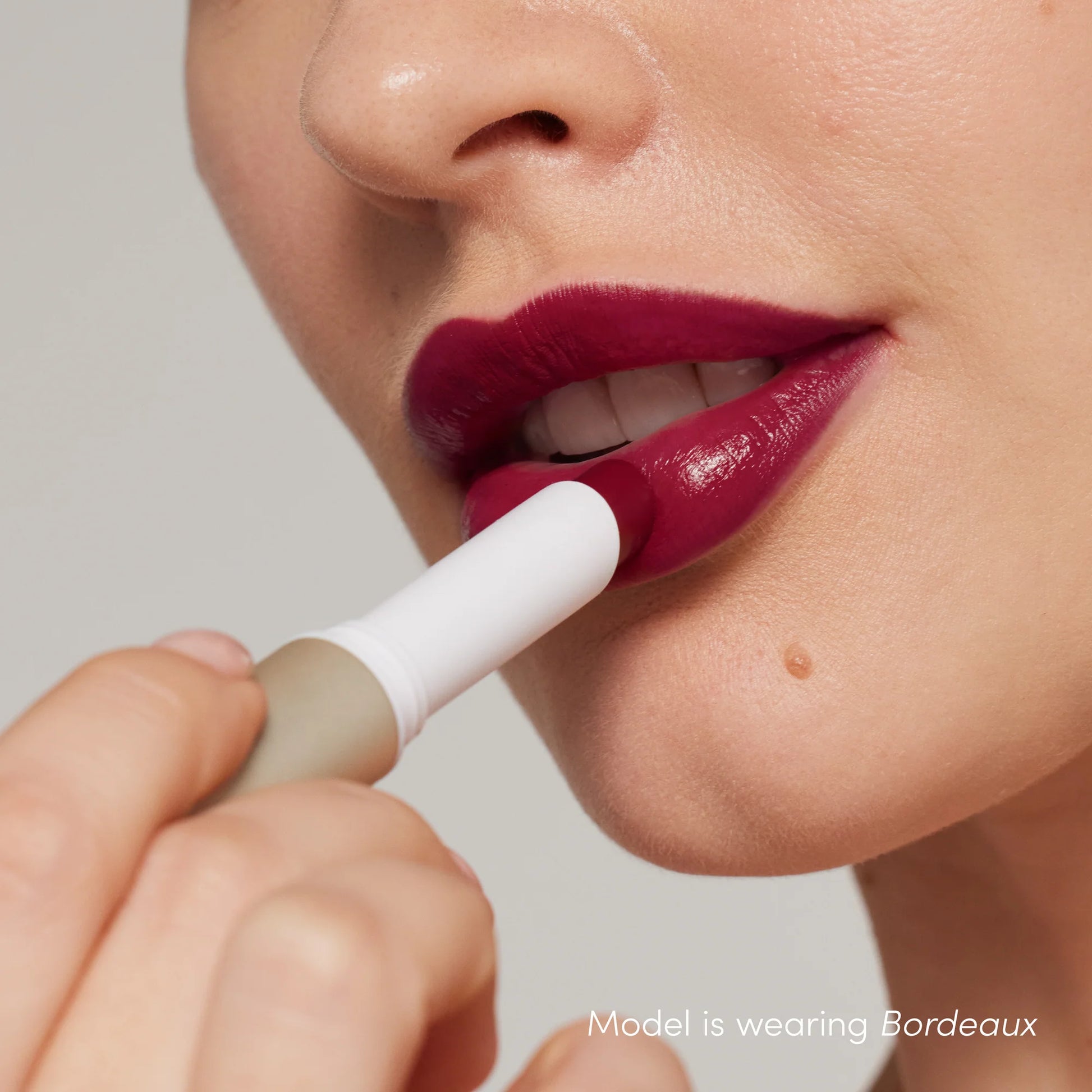 Applying ColorLuxe Hydrating Cream Lipstick in Bordeaux, highlighting its creamy texture and hydrating formula for vibrant, comfortable all-day wear.