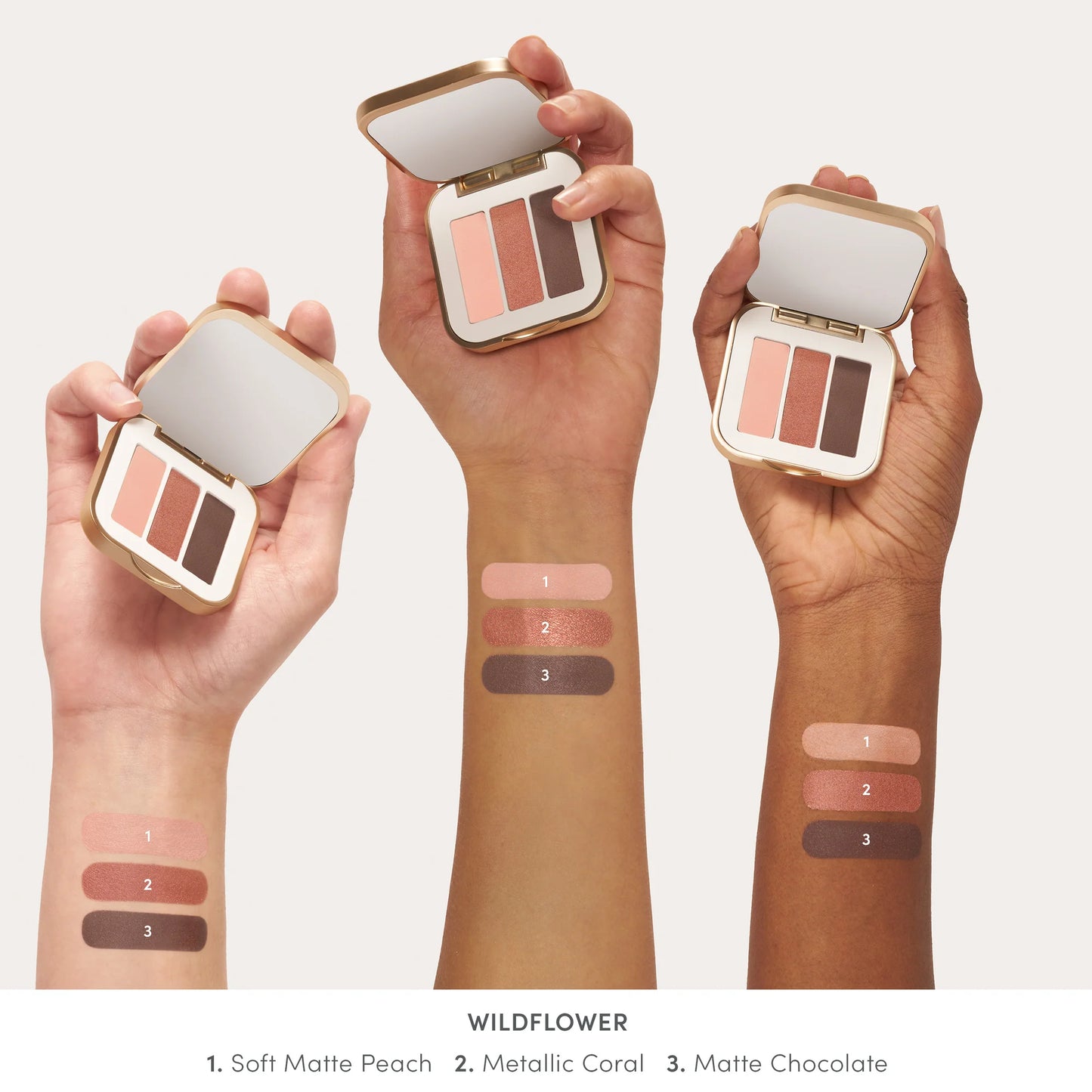 PurePressed® Eye Shadow Triple in Wildflower, a gold compact with mirror, featuring matte peach, metallic coral, and matte chocolate shades with swatches on three skin tones.