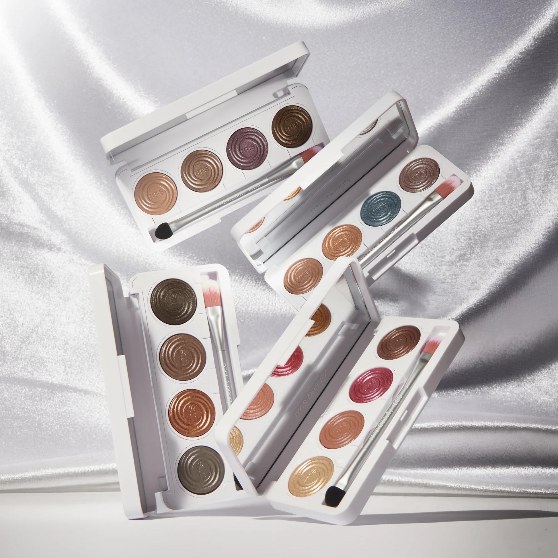 ReDimension Hydra Eyes Quartet makeup palettes with shimmery cream-to-powder eyeshadows, featuring a dual-ended brush on a satin background.