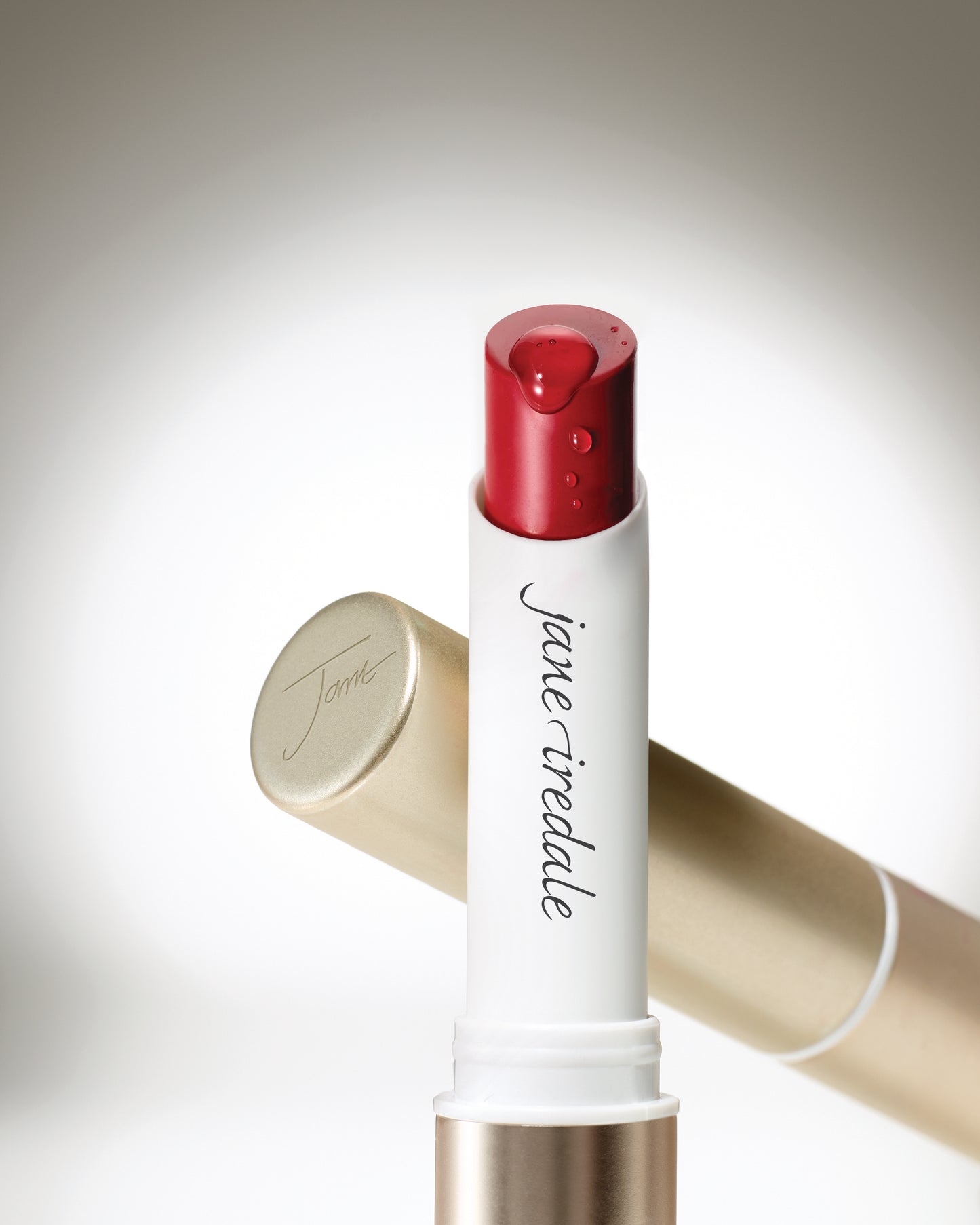 ColorLuxe Hydrating Cream Lipstick in a white tube with a gold cap, showcasing a red balm with a droplet on the tip.
