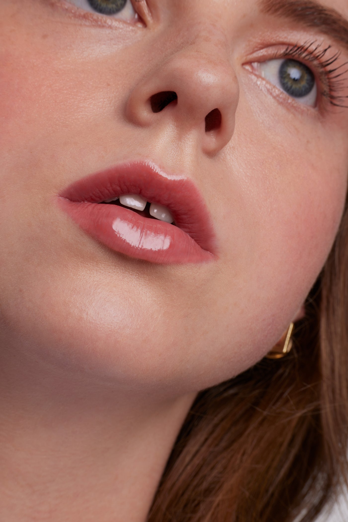 ColorLuxe High Impact Lip Glaze on glossy pink lips, showcasing smooth skin and subtle flush, emphasizing the product's high pigmentation and nourishing glossy finish.