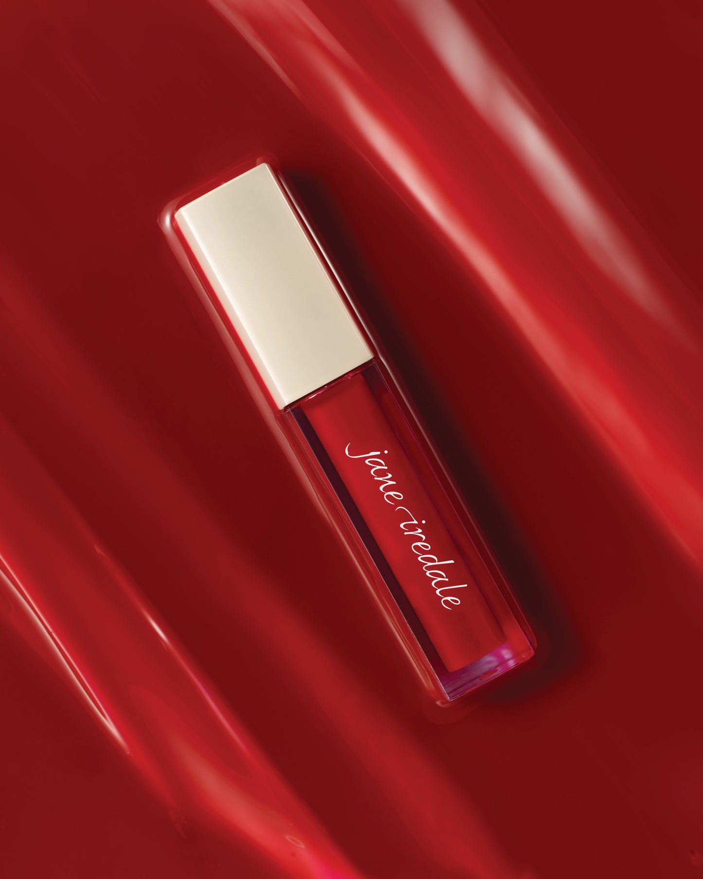 ColorLuxe High Impact Lip Glaze in vibrant red with an ivory cap, offering glossy, high-pigmentation color, visible through its clear tube, enhancing any makeup look.