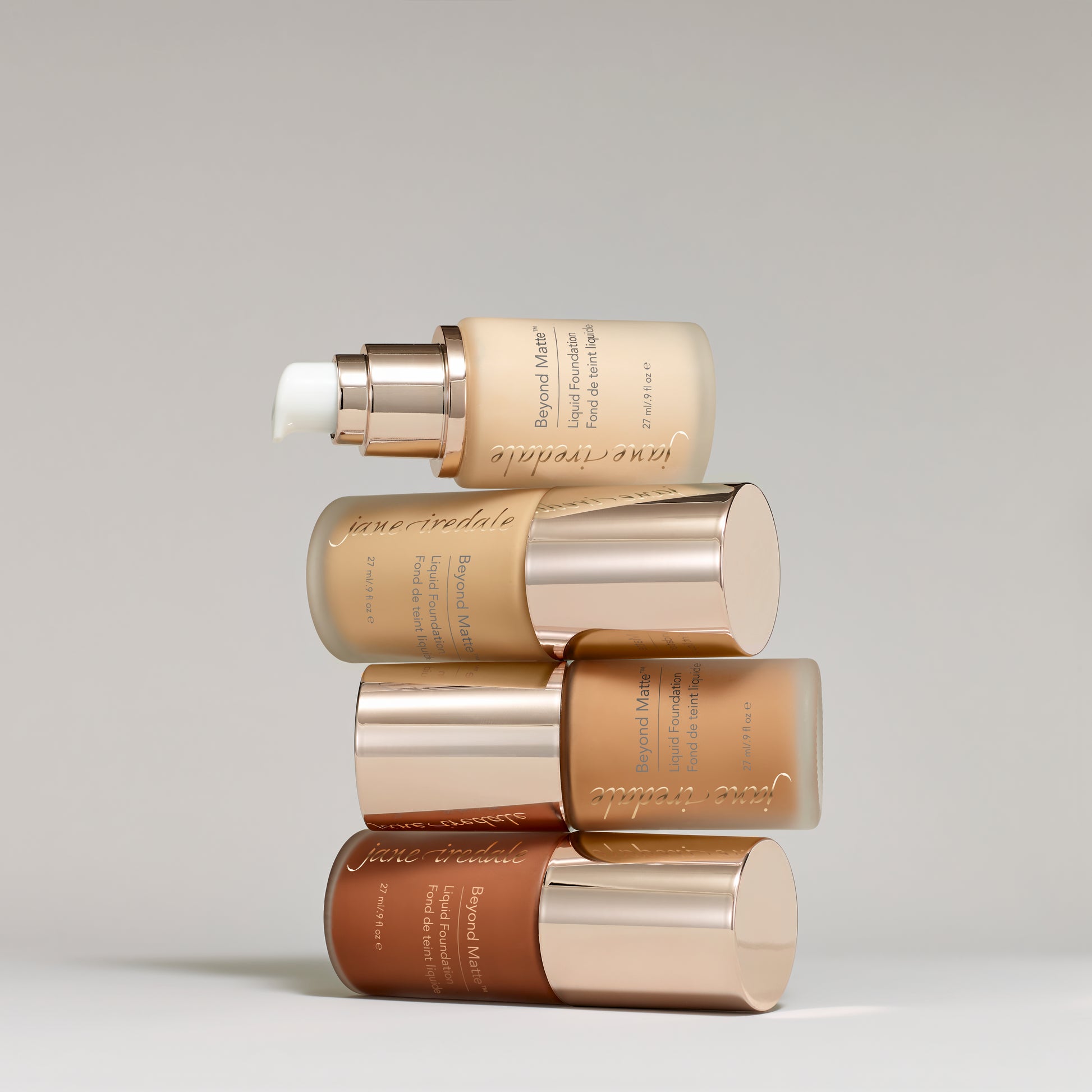 Frosted-glass foundation bottles with gold caps, showcasing Jane Iredale's Beyond Matte™ Liquid Foundation, offering buildable, semi-matte coverage with plant-based, pore-minimizing ingredients.