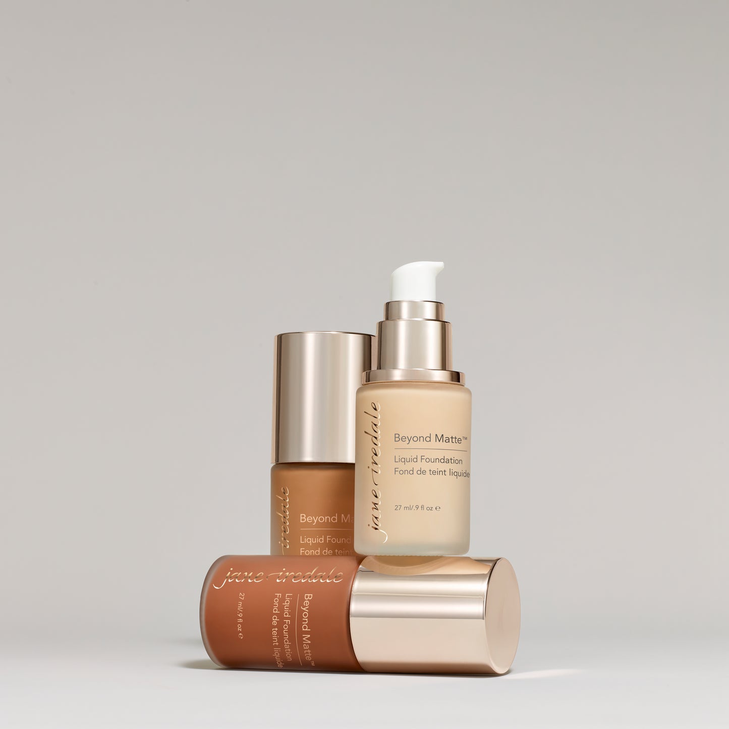 Jane Iredale Beyond Matte Liquid Foundation bottles arranged, showcasing three shades, highlighting its buildable coverage and semi-matte finish with skin-nourishing, plant-based ingredients.