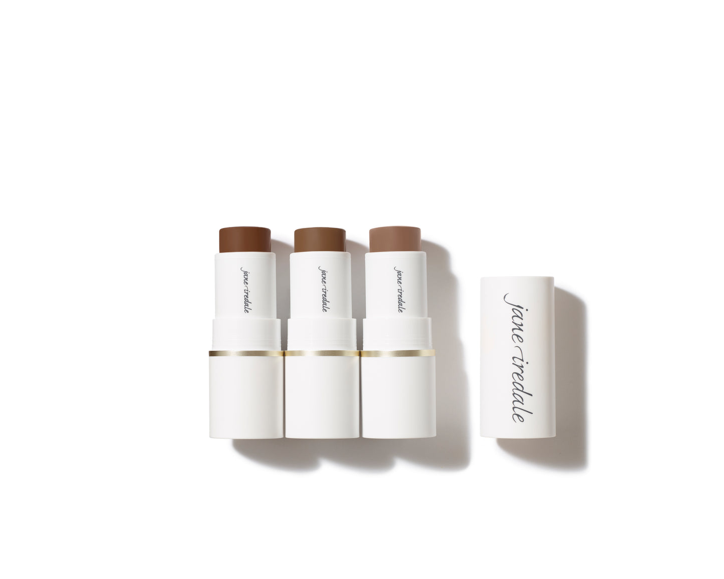 Three Glow Time® Bronzer Sticks in shades of medium-to-dark brown, displayed with caps, for a sun-kissed, buildable, and nourishing finish.