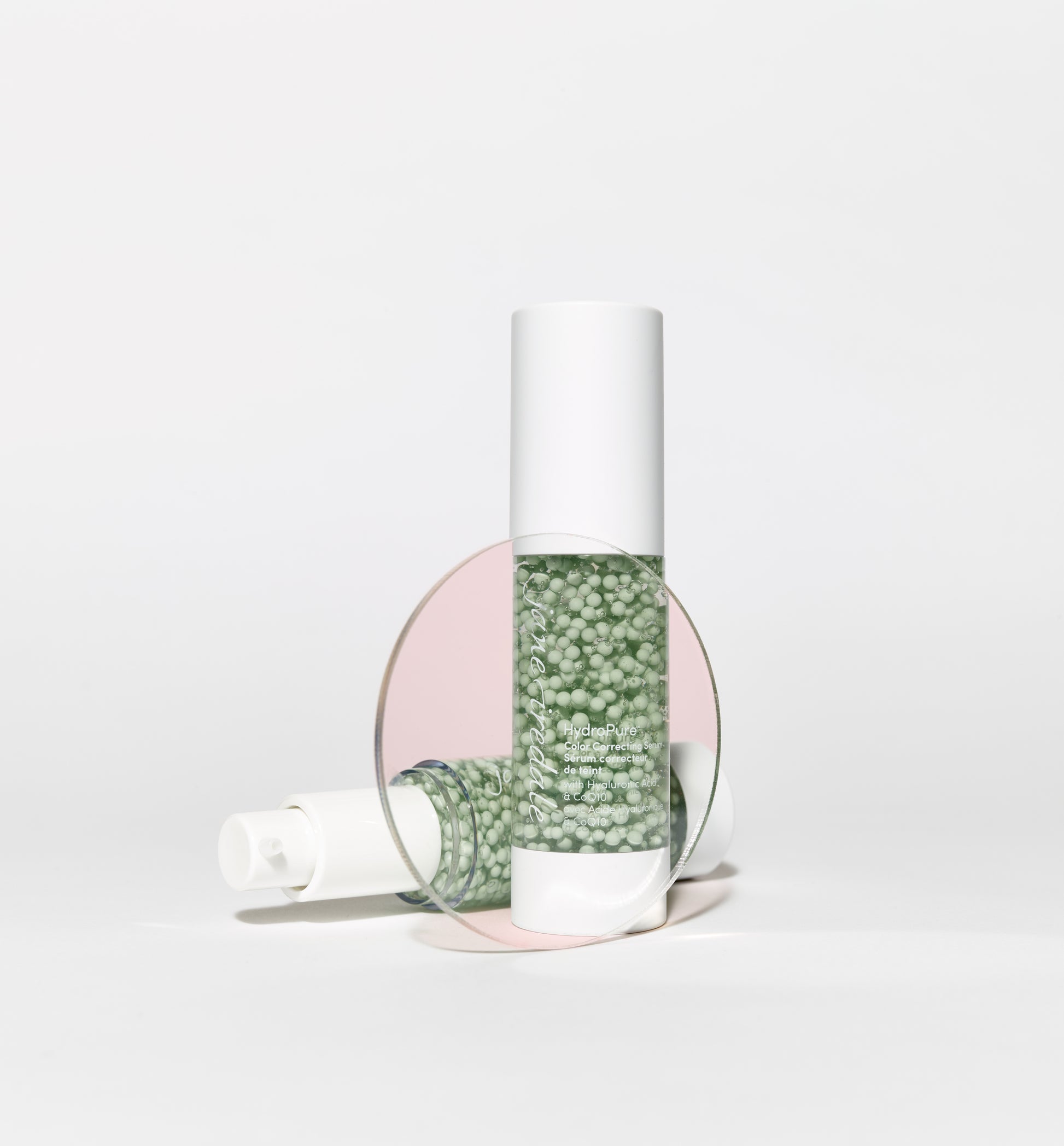 HydroPure™ Color Correcting Serum bottles, one upright, one lying down, feature pale green gel with beads; offers hydration and skin tone correction.