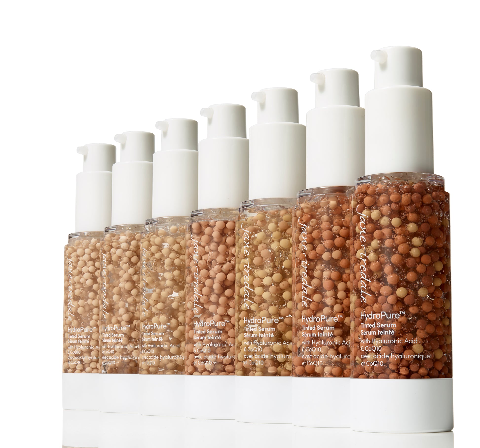 Row of Jane Iredale HydroPure™ Tinted Serum bottles with colored beads, ranging from light to dark shades, promising hydration and luminous finish.
