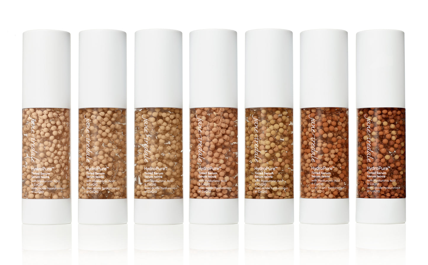 Seven HydroPure™ Tinted Serum bottles, lightest to darkest, with pigment beads in gel, offering hydration and luminous coverage with Hyaluronic Acid and CoQ10.