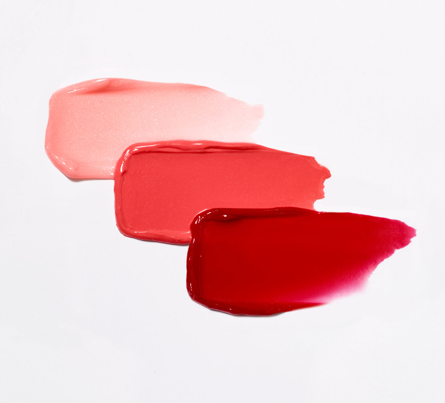HydroPure™ Hyaluronic Acid Lip Gloss swatches in pink, coral-pink, and red, showcasing high-shine, hydrating formula. Perfect for vibrant, healthy lips from Beauty Shop Bellaire.