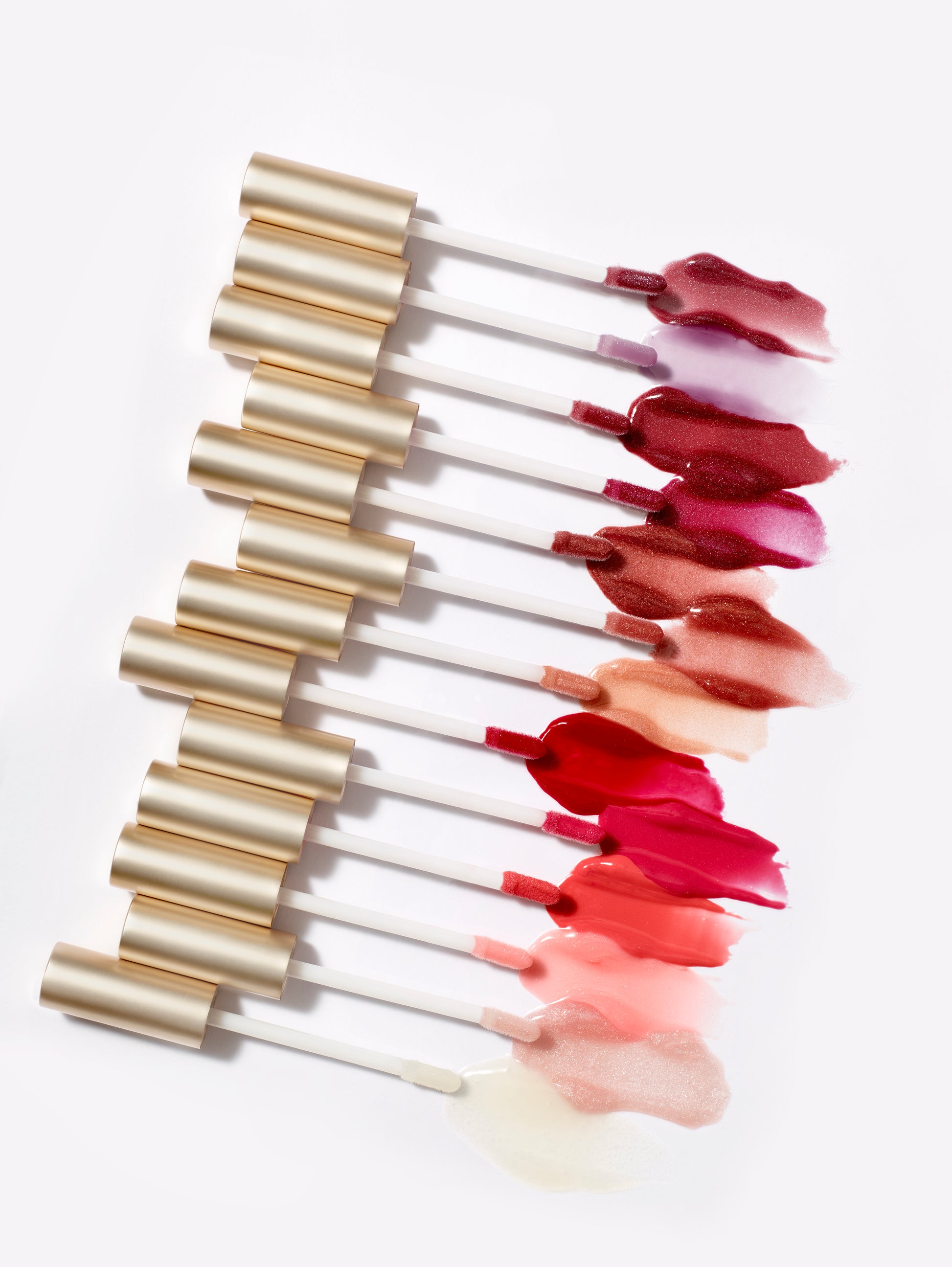 HydroPure™ Hyaluronic Acid Lip Gloss wands display nourishing, high-shine shades with gold caps, highlighting the product's hydrating, plumping features.