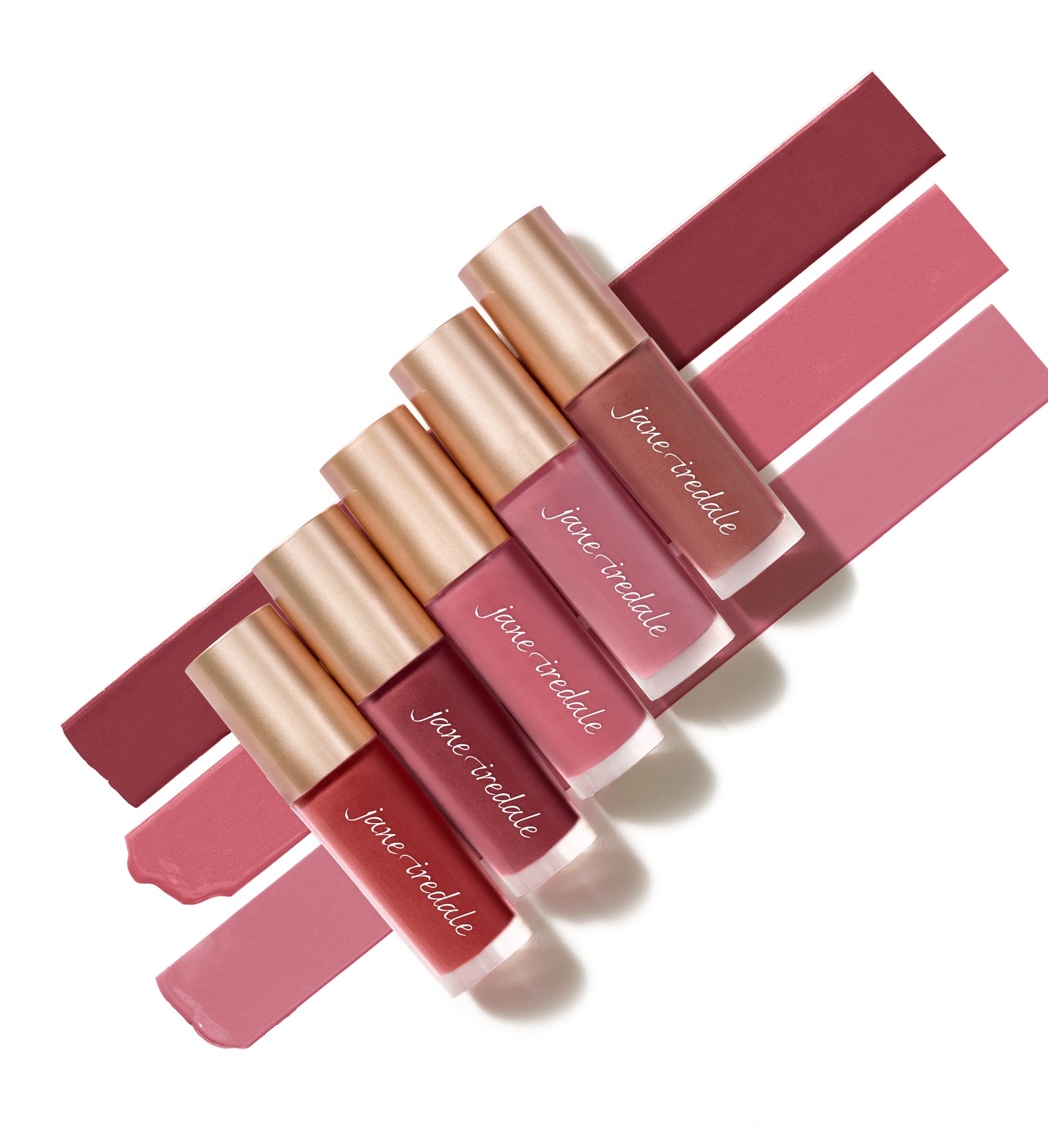Jane Iredale's Beyond Matte® Lip Stain tubes arranged with swatches, showcasing buildable, long-wearing colors from rose-pinks to mauves, each with champagne-gold caps.