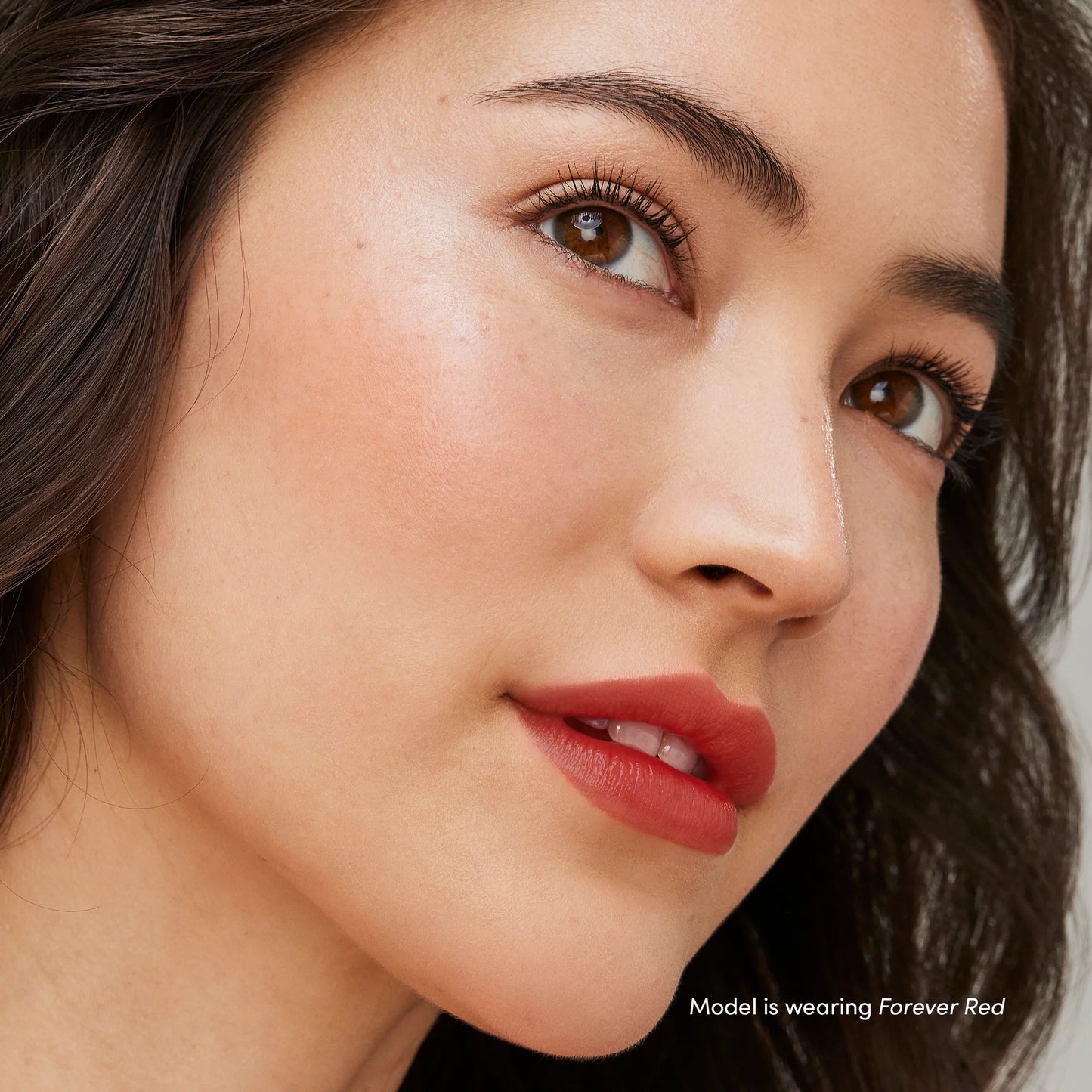 Close-up of a model wearing Just Kissed® Lip and Cheek Stain in Forever Red, showcasing smooth skin and bold lips.