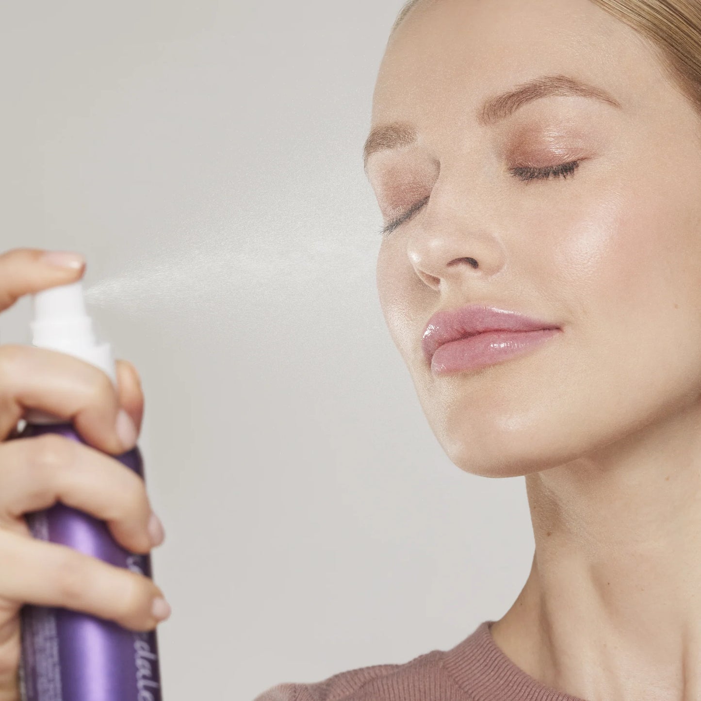 Woman's face being misted with Hydration Spray Calming Lavender, a soothing mist with organic lavender for hydrating and setting makeup, ideal for sensitive skin.