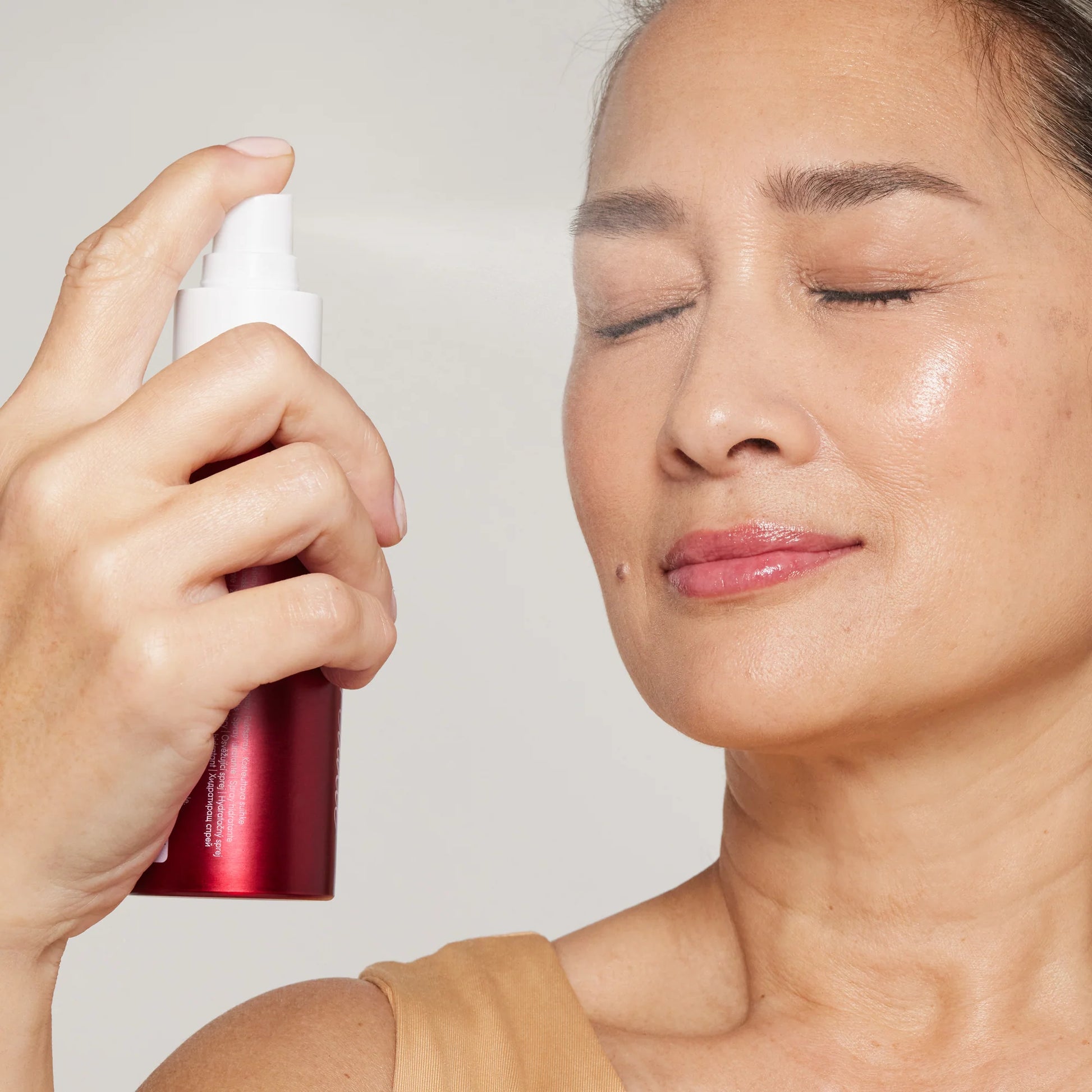 Person spraying Hydration Spray Balance on their cheek, eyes closed, illustrating its use to hydrate and balance skin, ideal for combination or oily types.