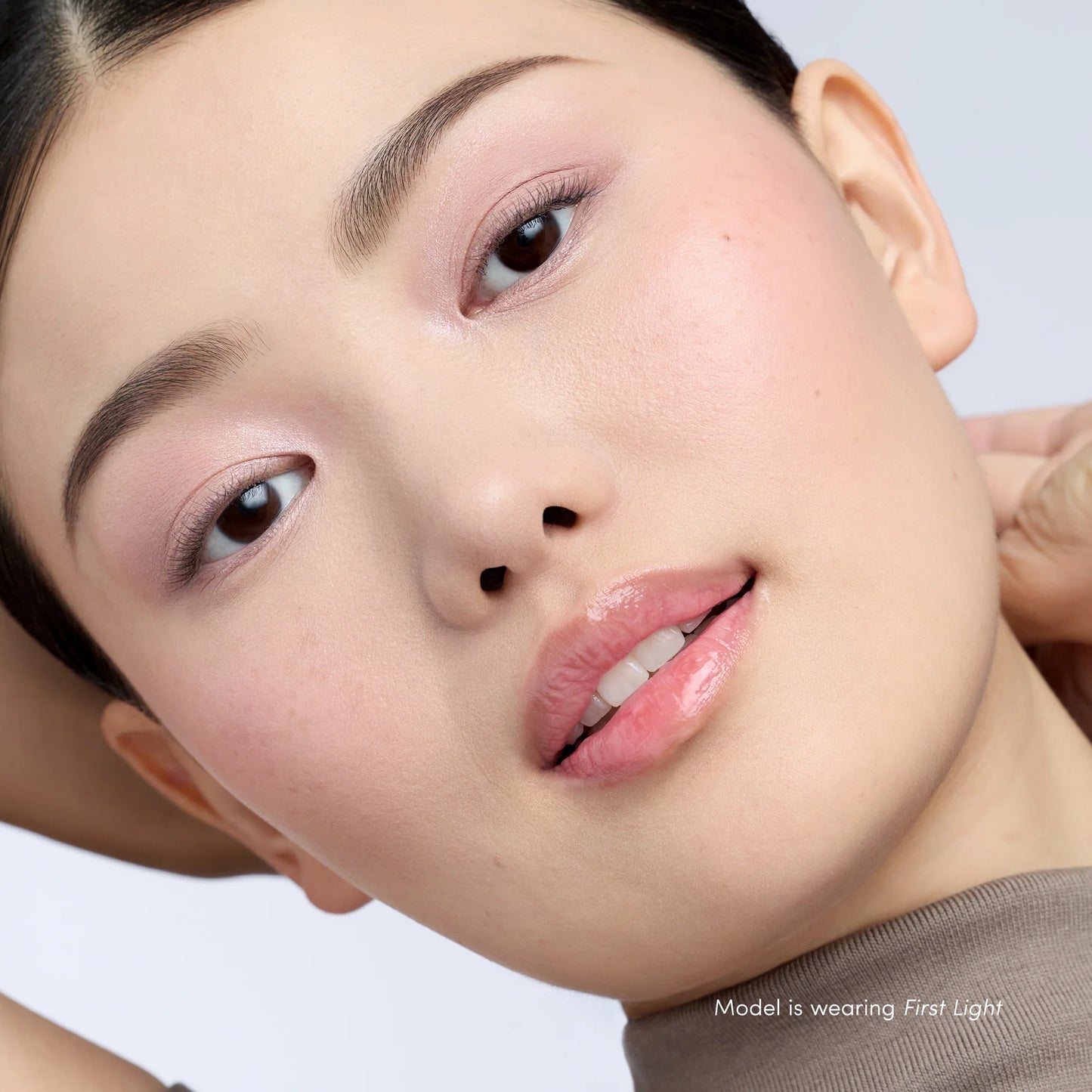 Close-up of a model's face showcasing soft pink eyeshadow, glossy lips, and smooth skin, highlighting the PureBronze™ Shimmer Bronzer Palette Refill in First Light.