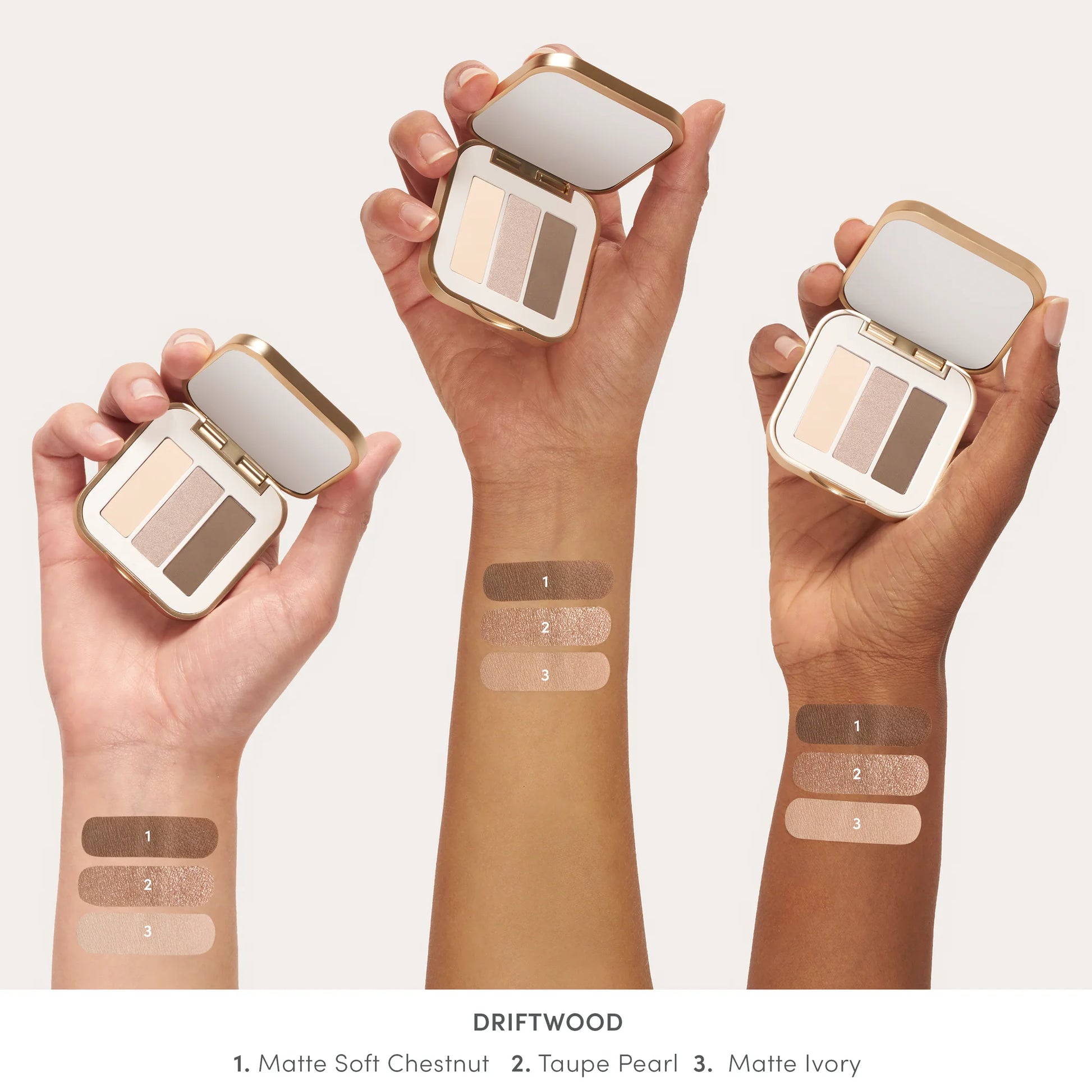 Hands holding PurePressed® Eye Shadow Triple compacts, featuring Driftwood shades with a built-in mirror and swatches on diverse skin tones.