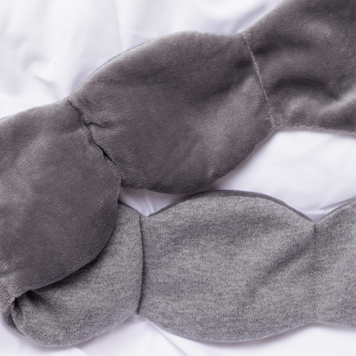 The Weighted Blanket for your Eyes: Two gray, contoured sleep masks with plush velvet and knit textures, designed for deep-touch pressure and soothing sleep.