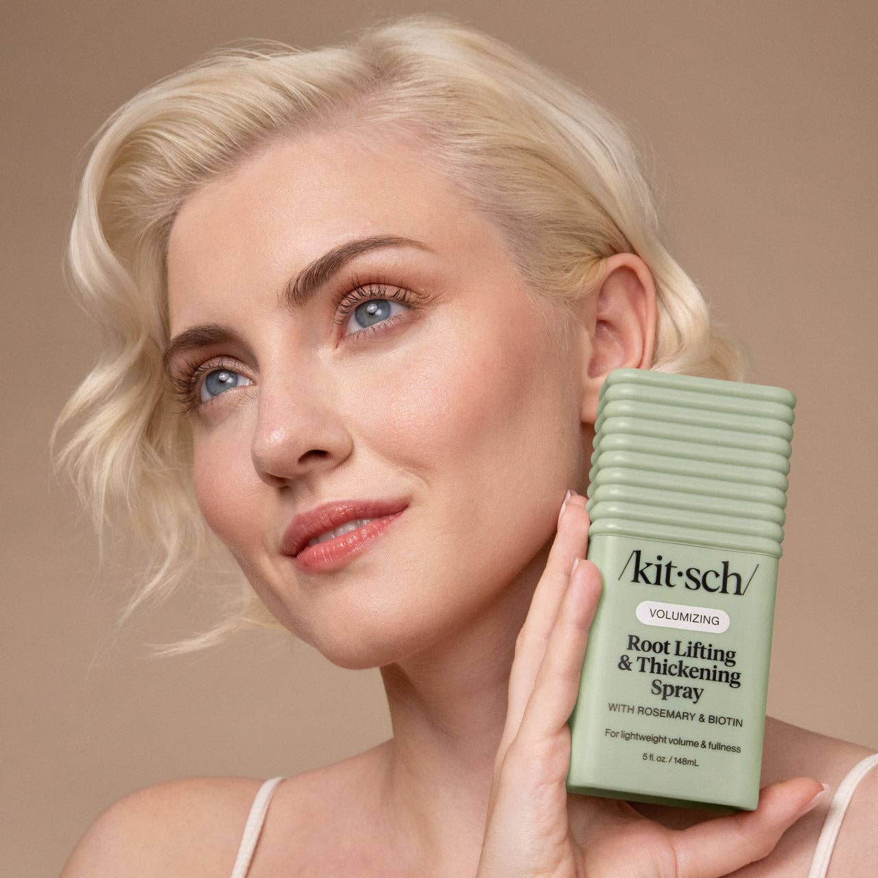 Woman holding Kitsch Volumizing Root Lifting & Thickening Spray, highlighting its lightweight volume and fullness benefits, featuring rosemary and biotin.