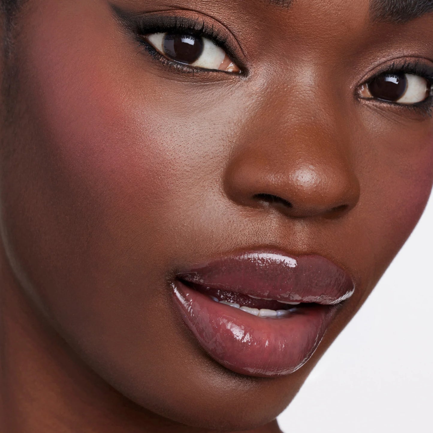 Close-up of a woman's face showcasing the Glow Time® Blush Stick's natural, skin-like finish with rosy-brown lips and neutral eye makeup.