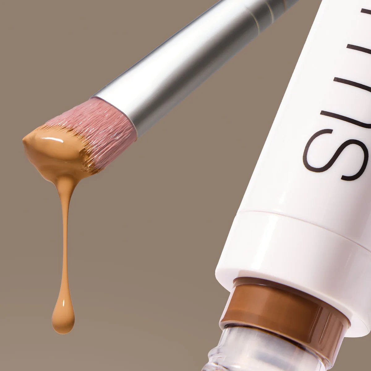 Skin2Skin Concealer Brush with beige foundation on bristles, featuring soft, vegan imitation goat hair for flawless, airbrushed blending of liquid and cream concealers.