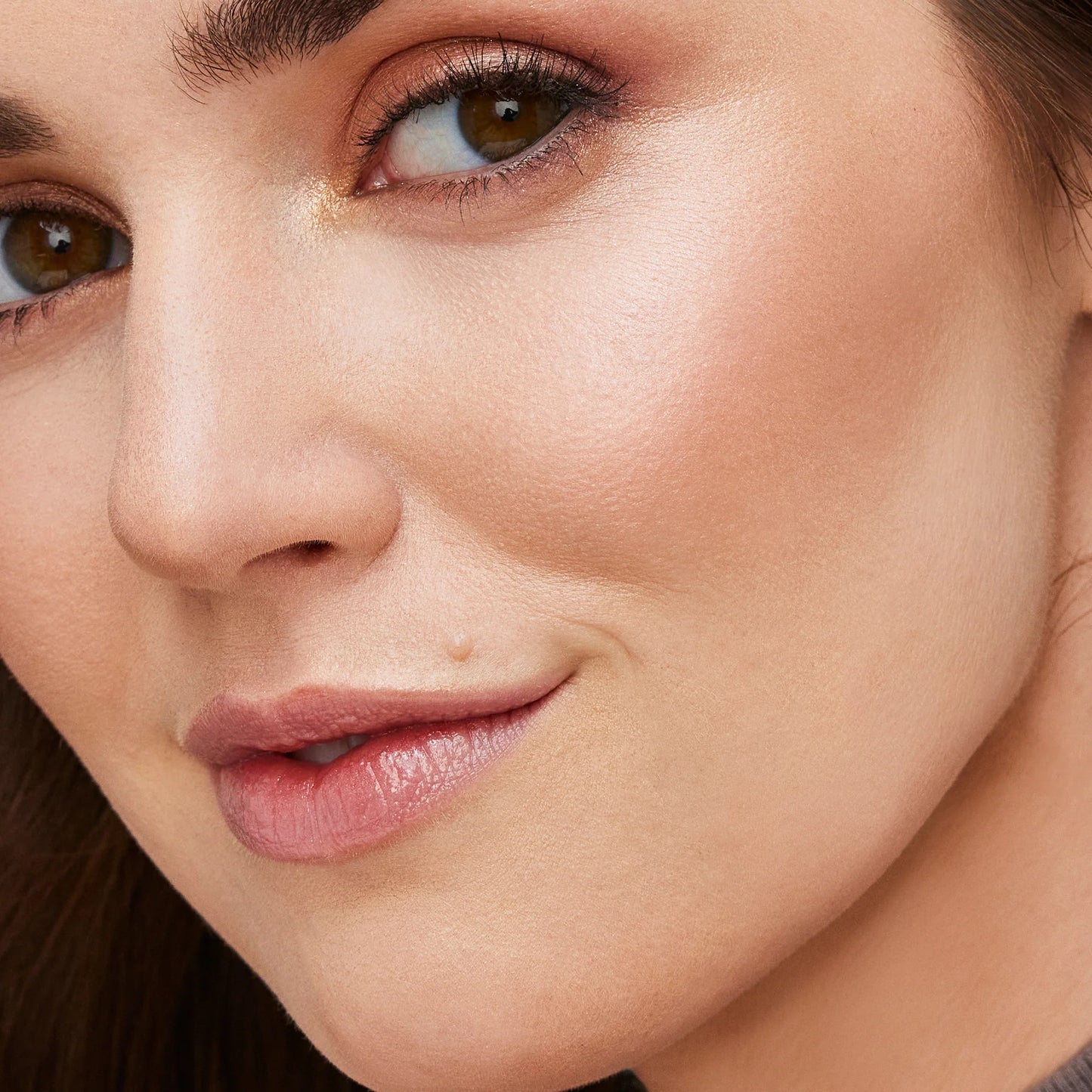 Close-up of a woman's face highlighting smooth skin, subtle makeup, and glossy lips, showcasing the Glow Time® Bronzer Stick's natural, sun-kissed finish.